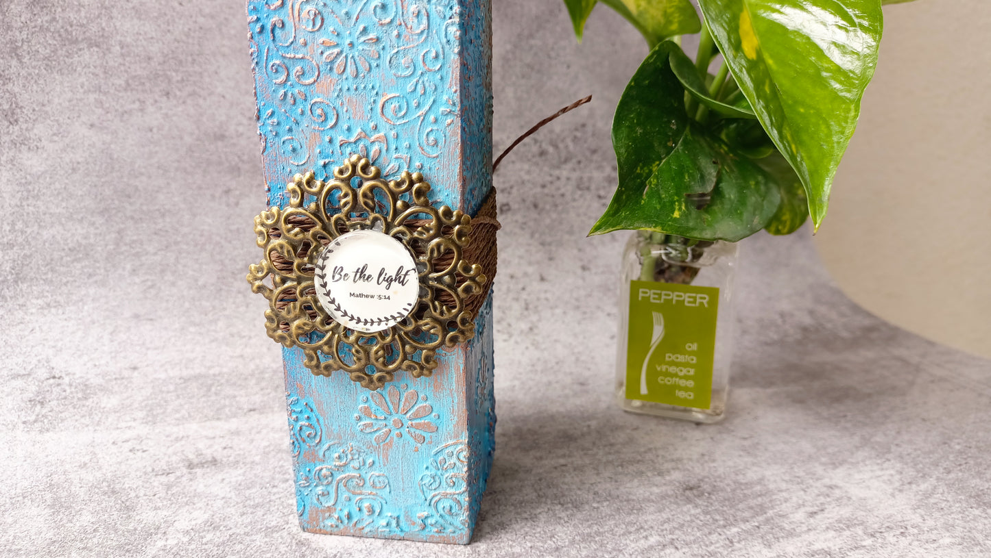Close-up of blue candle stand with 'Be the light' design