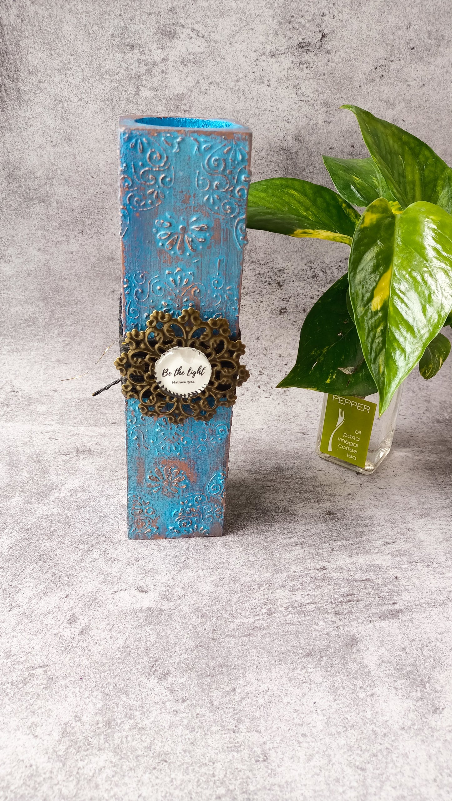 Tall blue candle stand with decorative 'Be the light' plaque