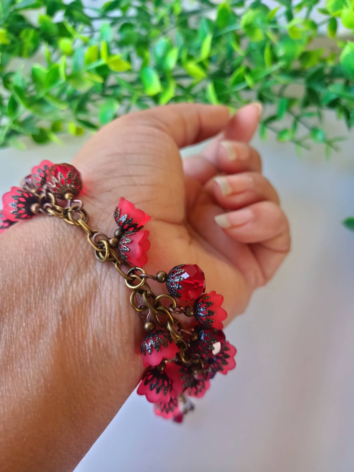 Efflorescence bracelet with red floral charms on wrist