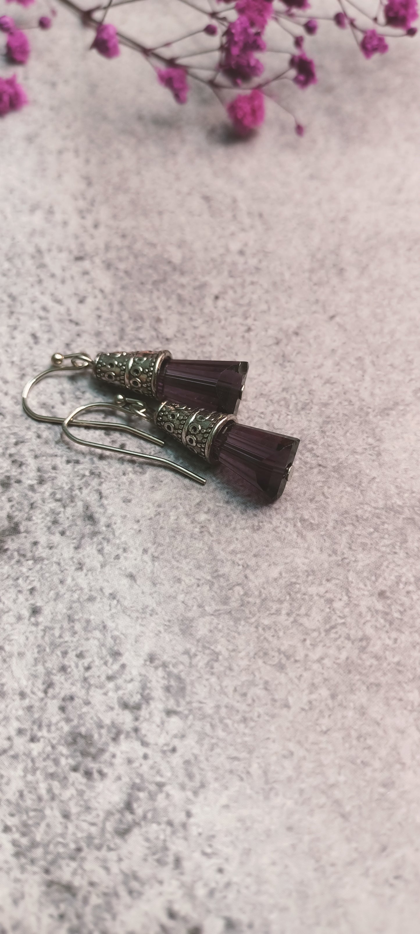 Close-up of purple glass bead earrings with metal accents