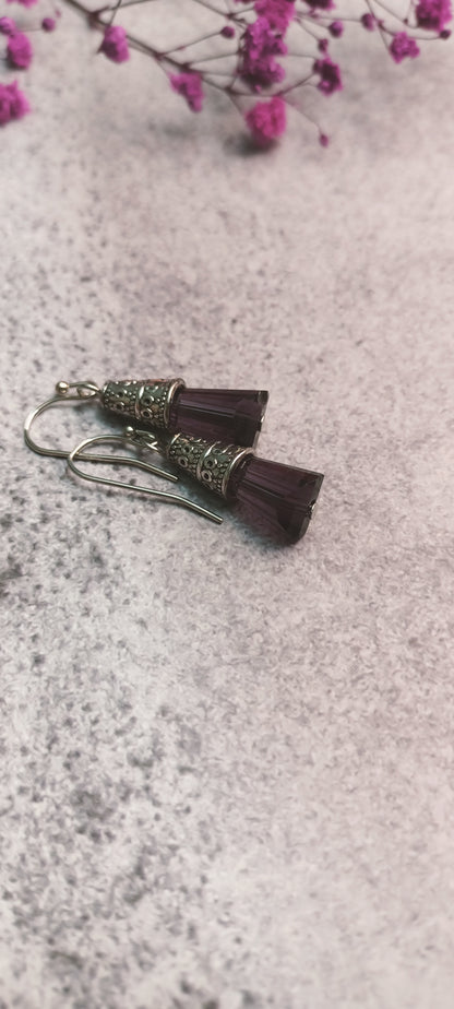 Close-up of purple glass bead earrings with metal accents