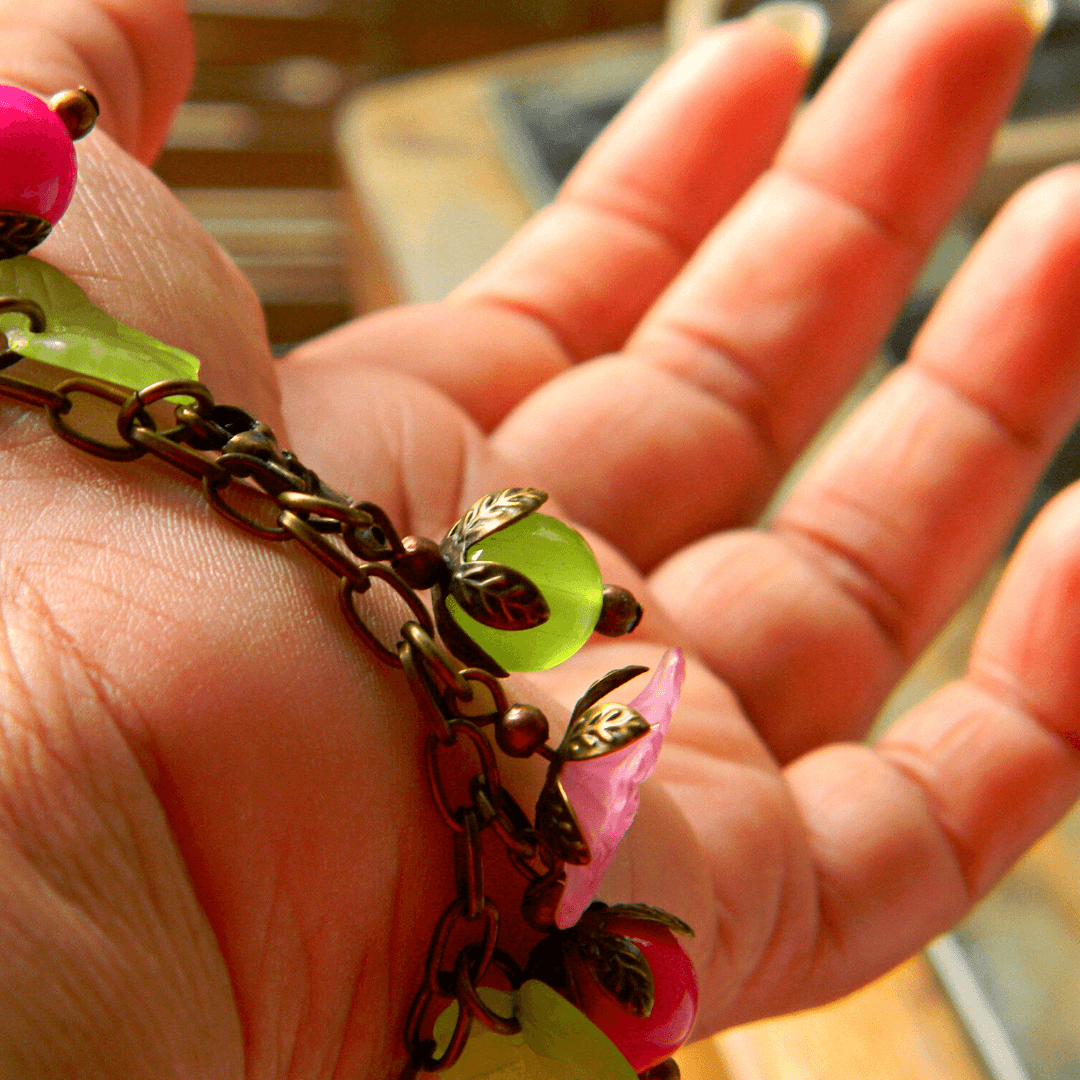 Detailed view of bracelet with pink and green beads in hand.