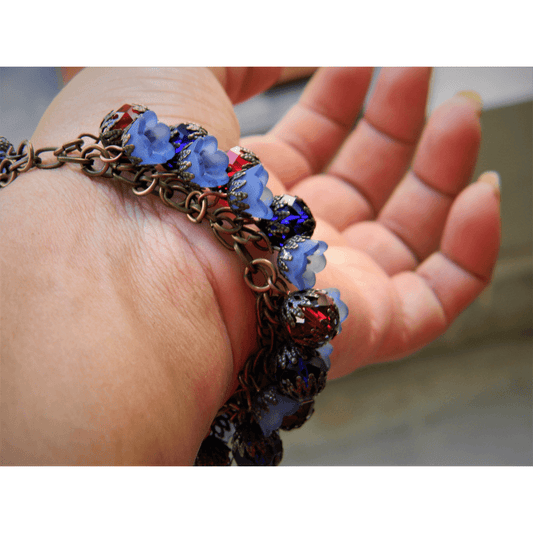 Efflorescence bracelet with blue and red floral charms on hand