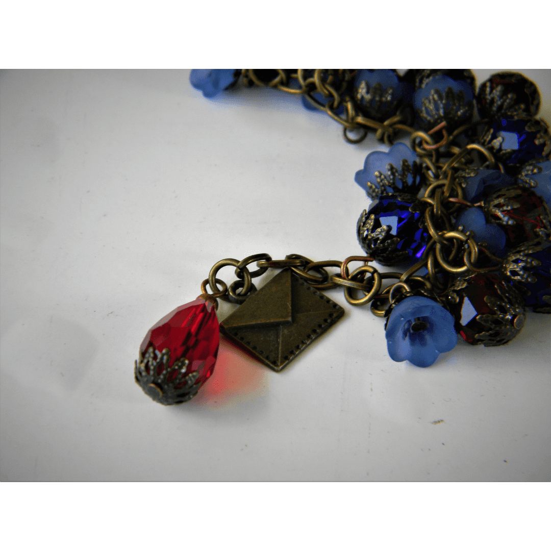 Close-up of Efflorescence bracelet with red charm and envelope