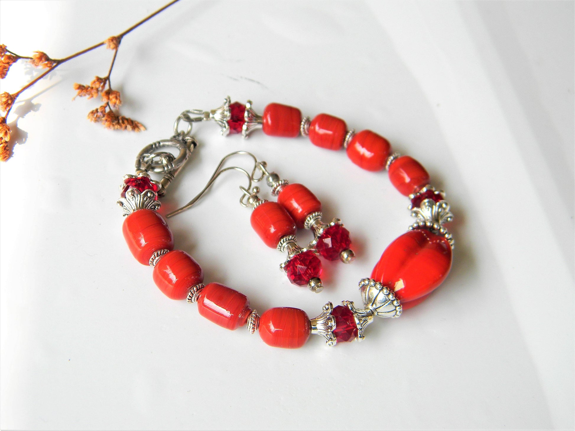 Elegant red glass bead bracelet and earrings on white background